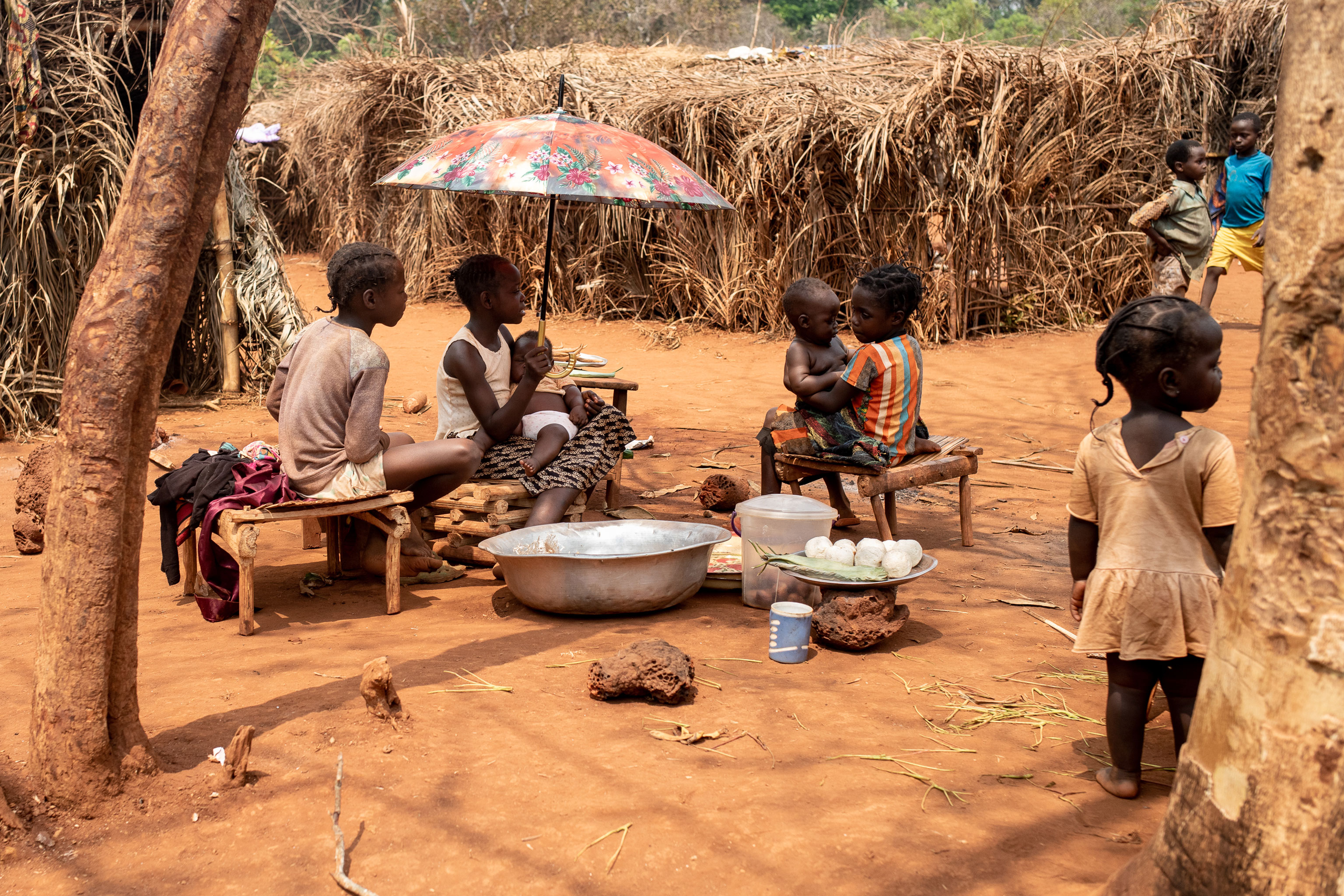 young children sitting in an arid area with small food for sale