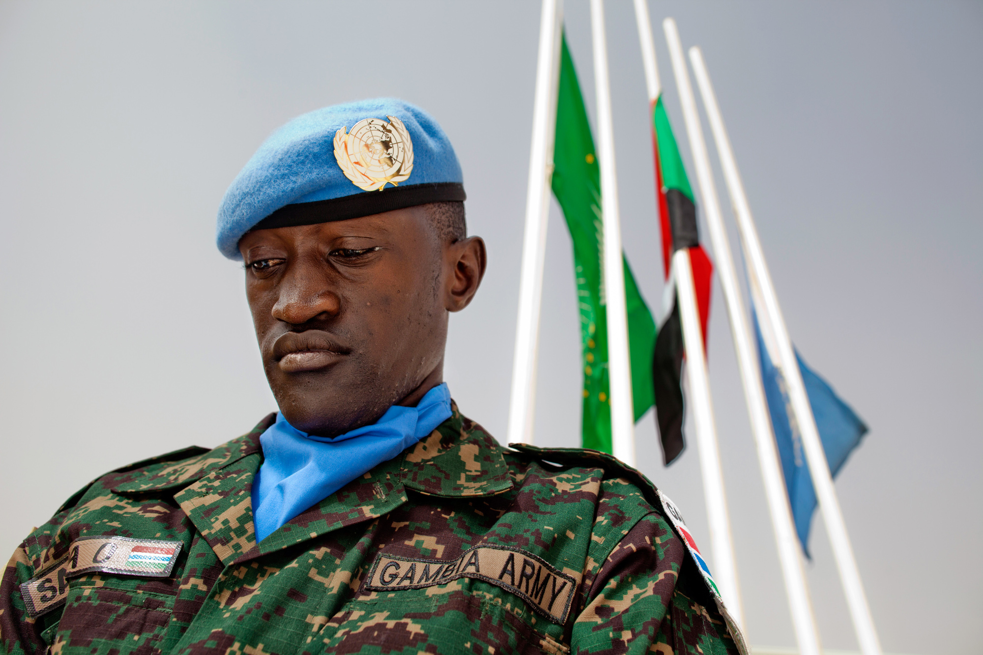 UN peacekeeper, head down, under three flags.